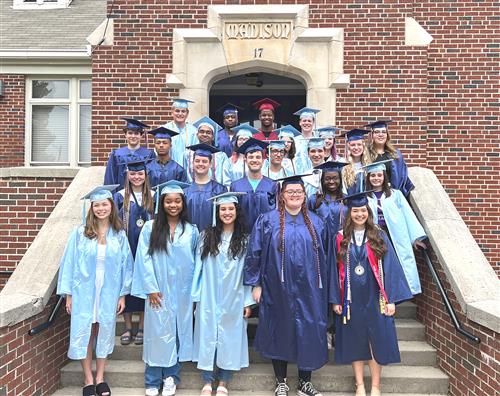 about two dozen seniors in caps and gowns on steps of Madison Elementary